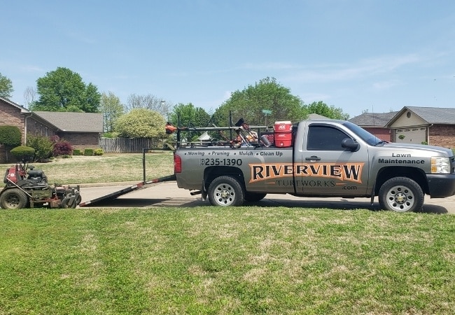 A lawn mower being unloaded from a Riverview Turfworks work truck.